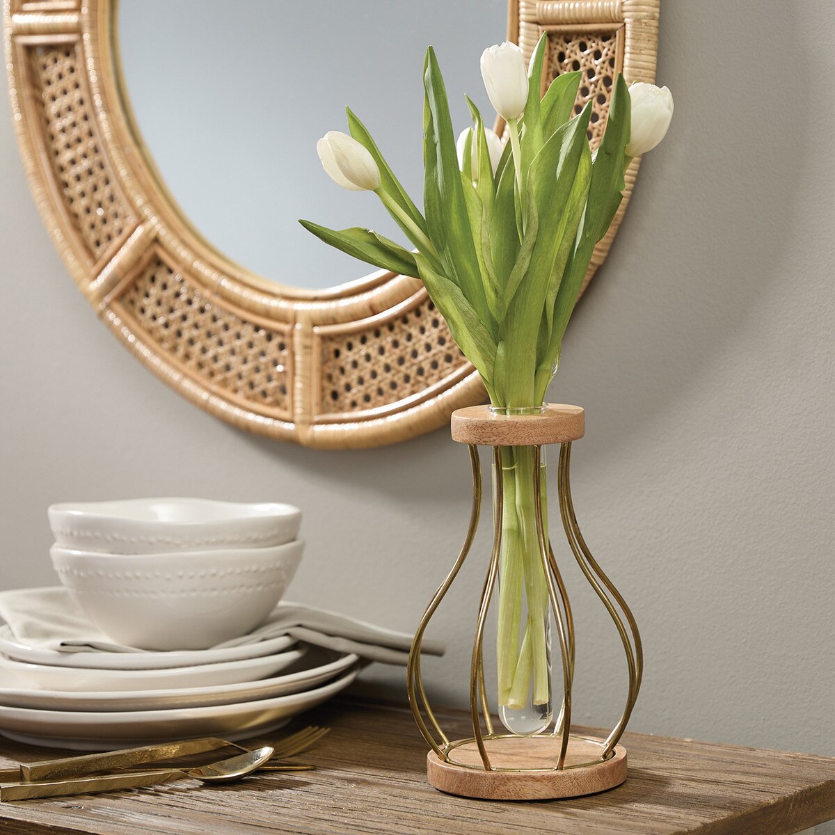 Decorative vase with tulips on a table against a wall with a round mirror.